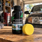 Lensmith headlight polish bottle and sponge on a garage workbench in front of a car